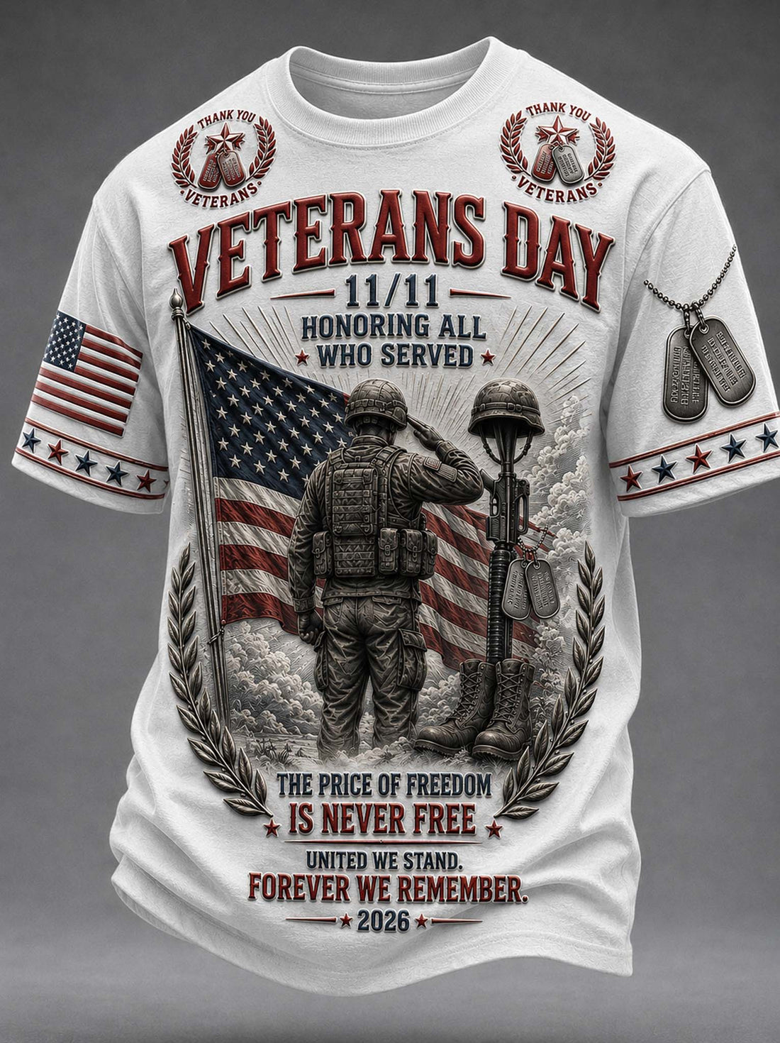 A white short-sleeve graphic t-shirt featuring a detailed Veterans Day design. The graphic includes a saluting soldier, an American flag, dog tags, laurel wreaths, and patriotic text reading 'VETERANS DAY 11/11 HONORING ALL WHO SERVED' and 'THE PRICE OF FREEDOM IS NEVER FREE FOREVER WE REMEMBER 2026'.
