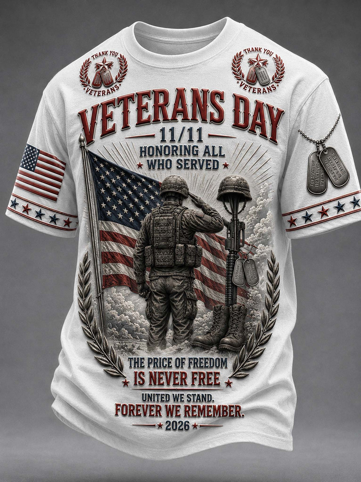 A white short-sleeve graphic t-shirt featuring a detailed Veterans Day design. The graphic includes a saluting soldier, an American flag, dog tags, laurel wreaths, and patriotic text reading 'VETERANS DAY 11/11 HONORING ALL WHO SERVED' and 'THE PRICE OF FREEDOM IS NEVER FREE FOREVER WE REMEMBER 2026'.