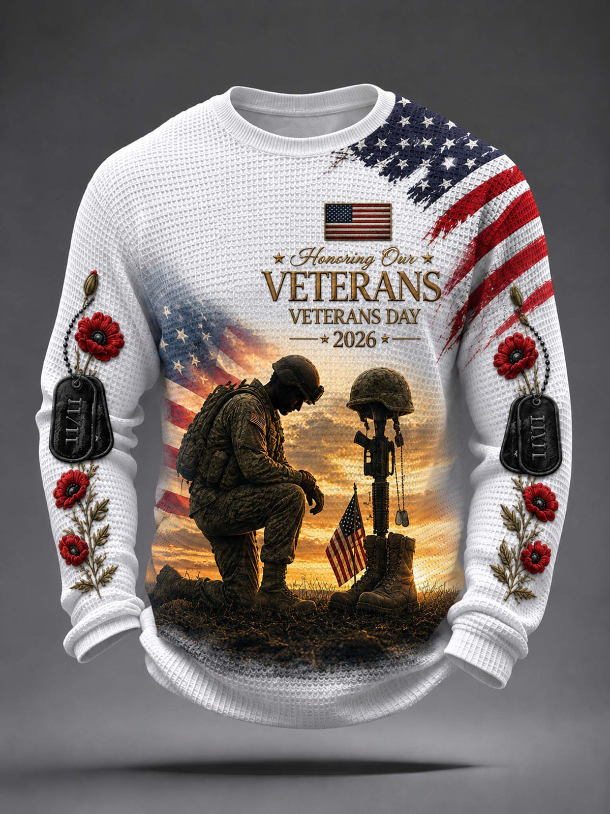 A white long-sleeve crewneck sweater featuring a detailed Veterans Day graphic. The design includes an American flag, a kneeling soldier, a helmet on a rifle, a sunset background, and red poppy flowers with black dog tags on the sleeves.