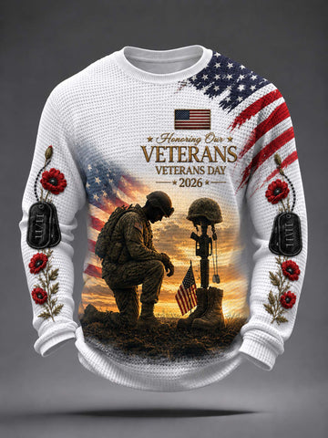 A white long-sleeve crewneck sweater featuring a detailed Veterans Day graphic. The design includes an American flag, a kneeling soldier, a helmet on a rifle, a sunset background, and red poppy flowers with black dog tags on the sleeves.