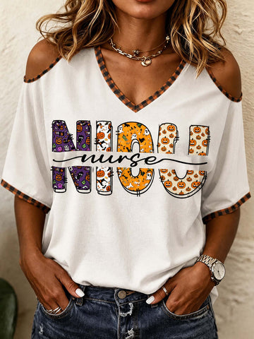 A woman wearing a white cold-shoulder V-neck t-shirt with orange and black striped trim, featuring a graphic that reads 'MORNING NURSE' in Halloween-themed patterns. She is also wearing blue jeans and a silver watch.