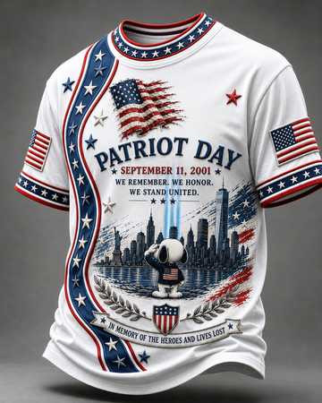A white short-sleeve t-shirt with a patriotic 'Patriot Day' graphic print. The design features red and blue stripes, white stars, American flags, a city skyline, a saluting Snoopy figure, and the text 'SEPTEMBER 11, 2001' and 'IN MEMORY OF THE HEROES AND LIVES LOST'.
