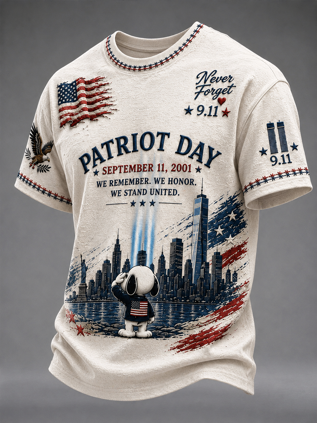 A cream-colored short-sleeve t-shirt featuring a detailed patriotic 9/11 themed graphic print with Snoopy, the New York City skyline, and American flag motifs, set against a neutral gray background.