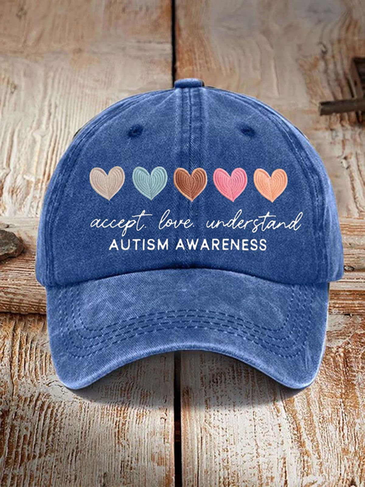 Blue cap with heart symbols and 'Autism Awareness' text on a wooden surface