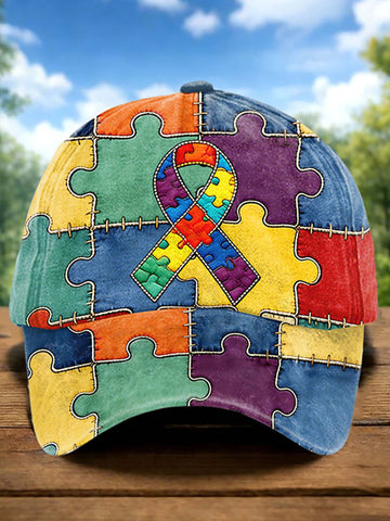 Colorful puzzle-patterned cap with an autism awareness ribbon on a wooden surface with a blurred natural background.