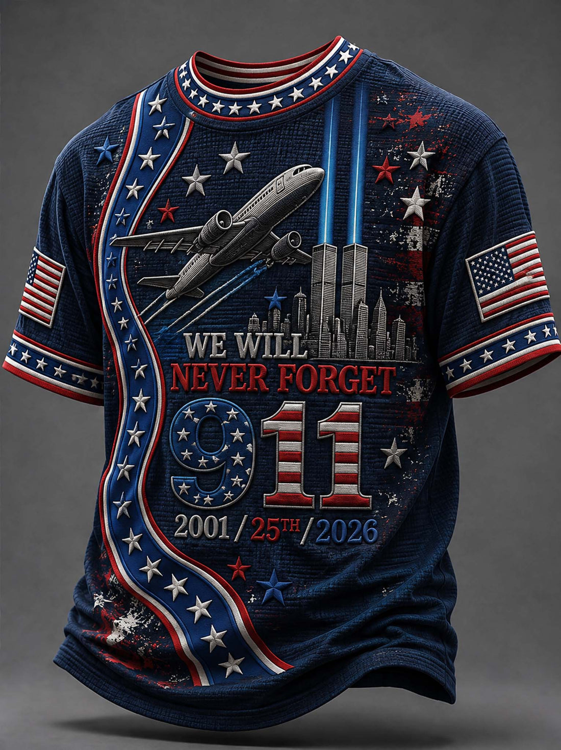 A navy blue short-sleeve t-shirt with a patriotic 9/11 memorial graphic. The design features red and white stripes, white stars, an airplane flying above the Twin Towers, and the text 'WE WILL NEVER FORGET 9/11 2001/25th/2026'.