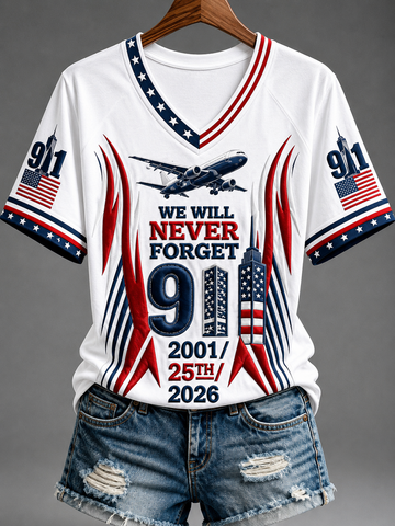 A white V-neck t-shirt with a patriotic 9/11 memorial graphic, styled on a wooden hanger with distressed denim shorts against a gray background.