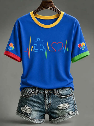 A blue short-sleeve ringer T-shirt with a yellow collar and red, green, and blue sleeve/cross graphics, styled with distressed denim shorts on a hanger against a gray background.