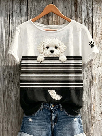 White t-shirt with a dog graphic and black stripes, worn with denim shorts, on a wooden background.