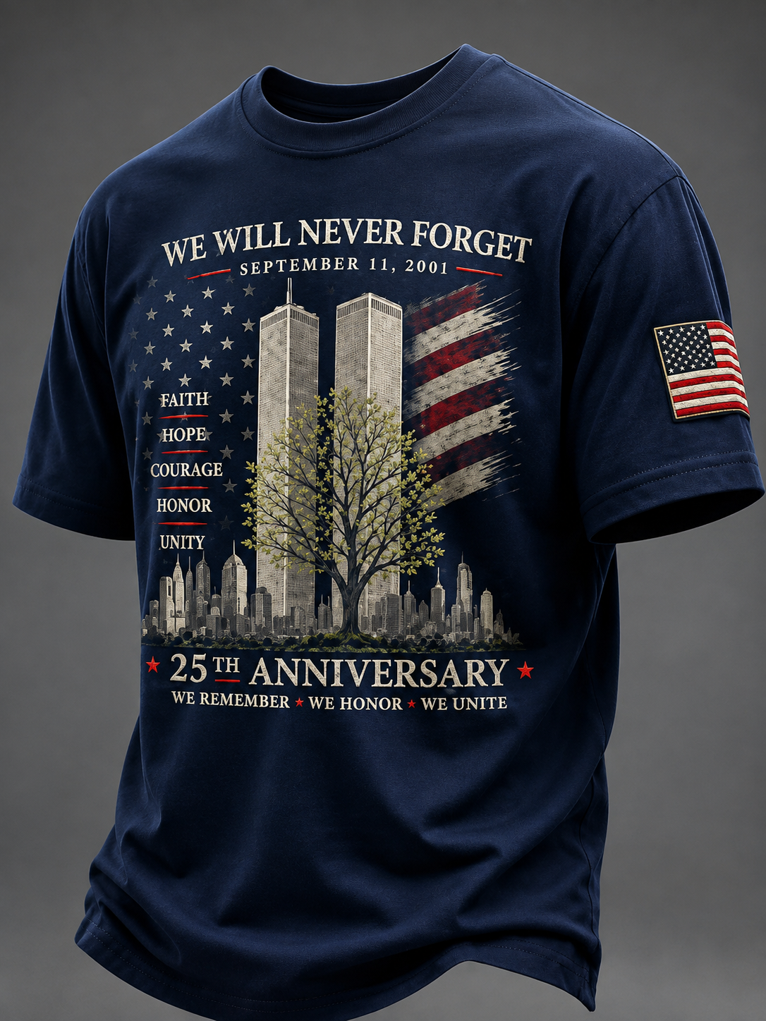 A navy blue short-sleeve t-shirt with a detailed 9/11 memorial graphic on the front, featuring the Twin Towers, an American flag, a tree, and the text 'We Will Never Forget' and '25th Anniversary'. It has an American flag patch on the left sleeve and is shown against a dark gray background.