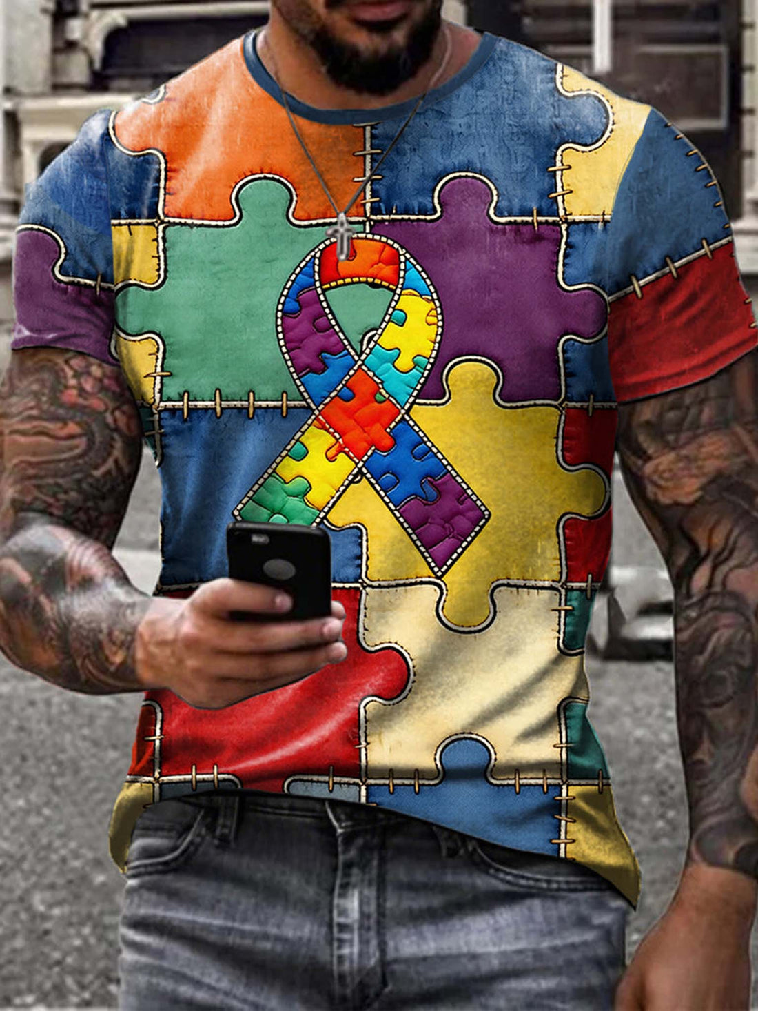 Person wearing a colorful puzzle-patterned shirt with an autism awareness ribbon.