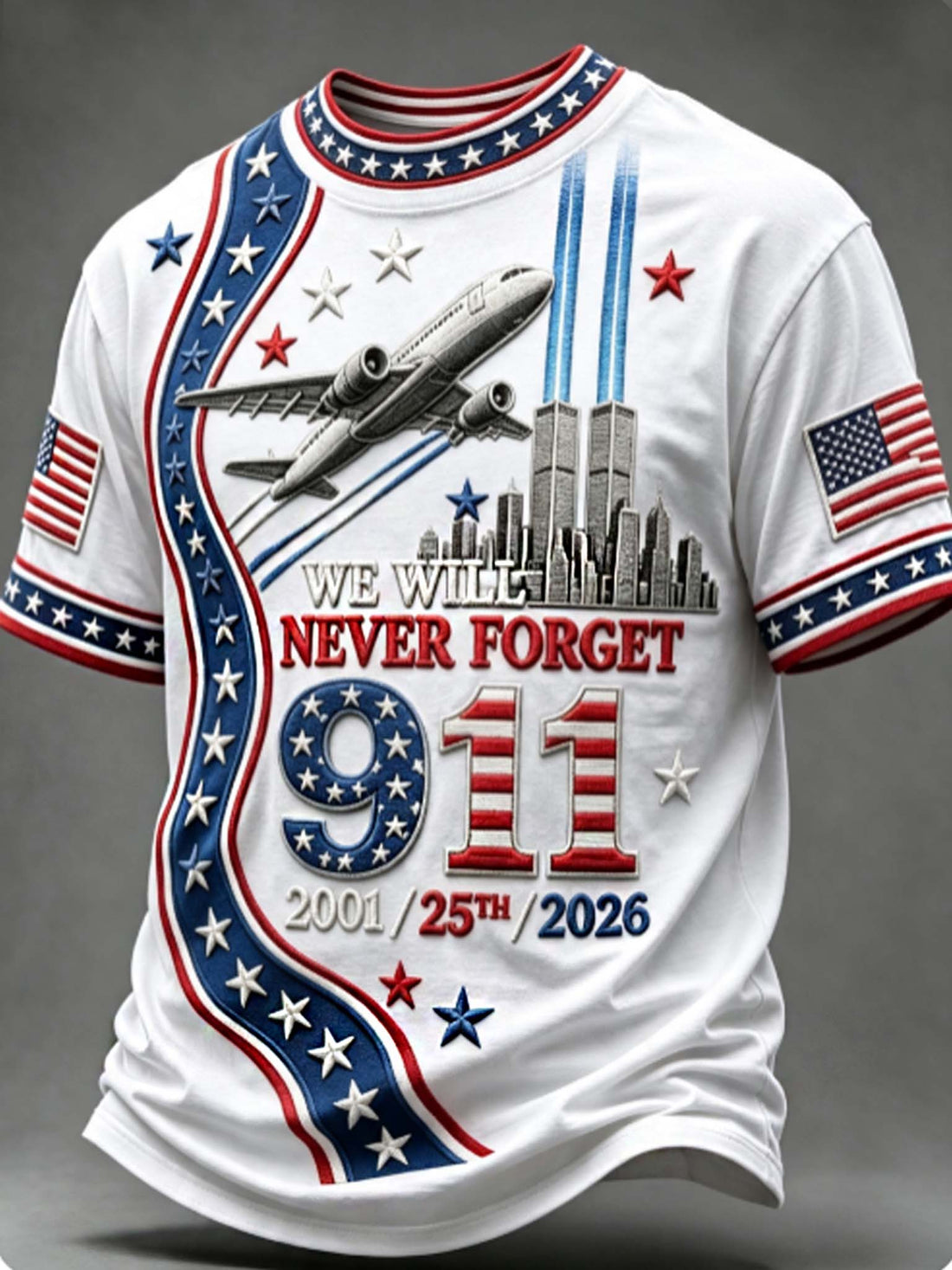 A white short-sleeve t-shirt with a patriotic 9/11 memorial graphic. The design features red and blue stripes, white stars, the text 'WE WILL NEVER FORGET 9/11 2001/25th/2026', an airplane flying above the Twin Towers, and American flags on both sleeves.
