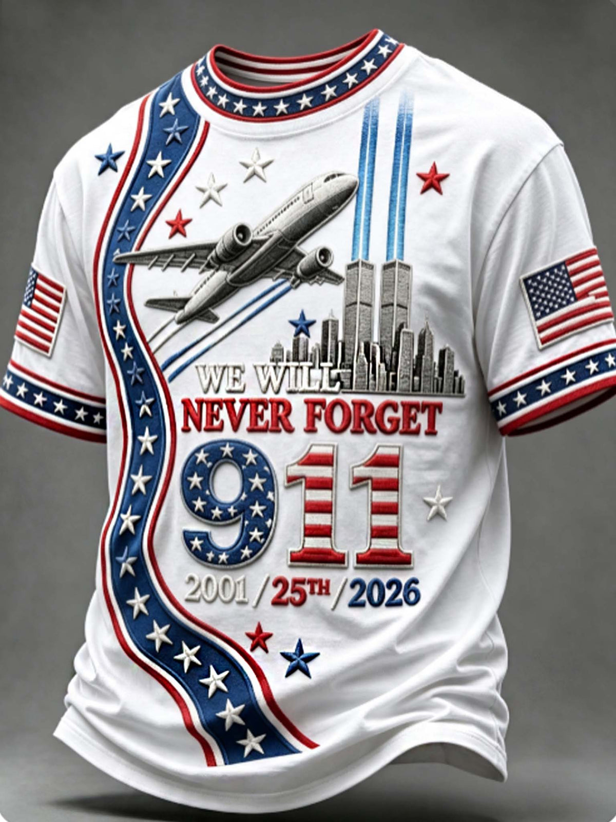 A white short-sleeve t-shirt with a patriotic 9/11 memorial graphic. The design features red and blue stripes, white stars, the text 'WE WILL NEVER FORGET 9/11 2001/25th/2026', an airplane flying above the Twin Towers, and American flags on both sleeves.