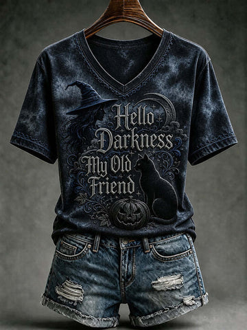 A dark acid-wash V-neck t-shirt with a Halloween graphic reading 'Hello Darkness My Old Friend' featuring a witch hat, cat, and pumpkin, styled on a wooden hanger with distressed denim shorts against a dark gray background.