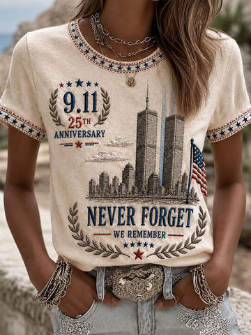 A woman wearing a cream-colored t-shirt with a patriotic 9/11 anniversary graphic featuring the Twin Towers, an American flag, and the text '9.11 25th Anniversary Never Forget We Remember'.