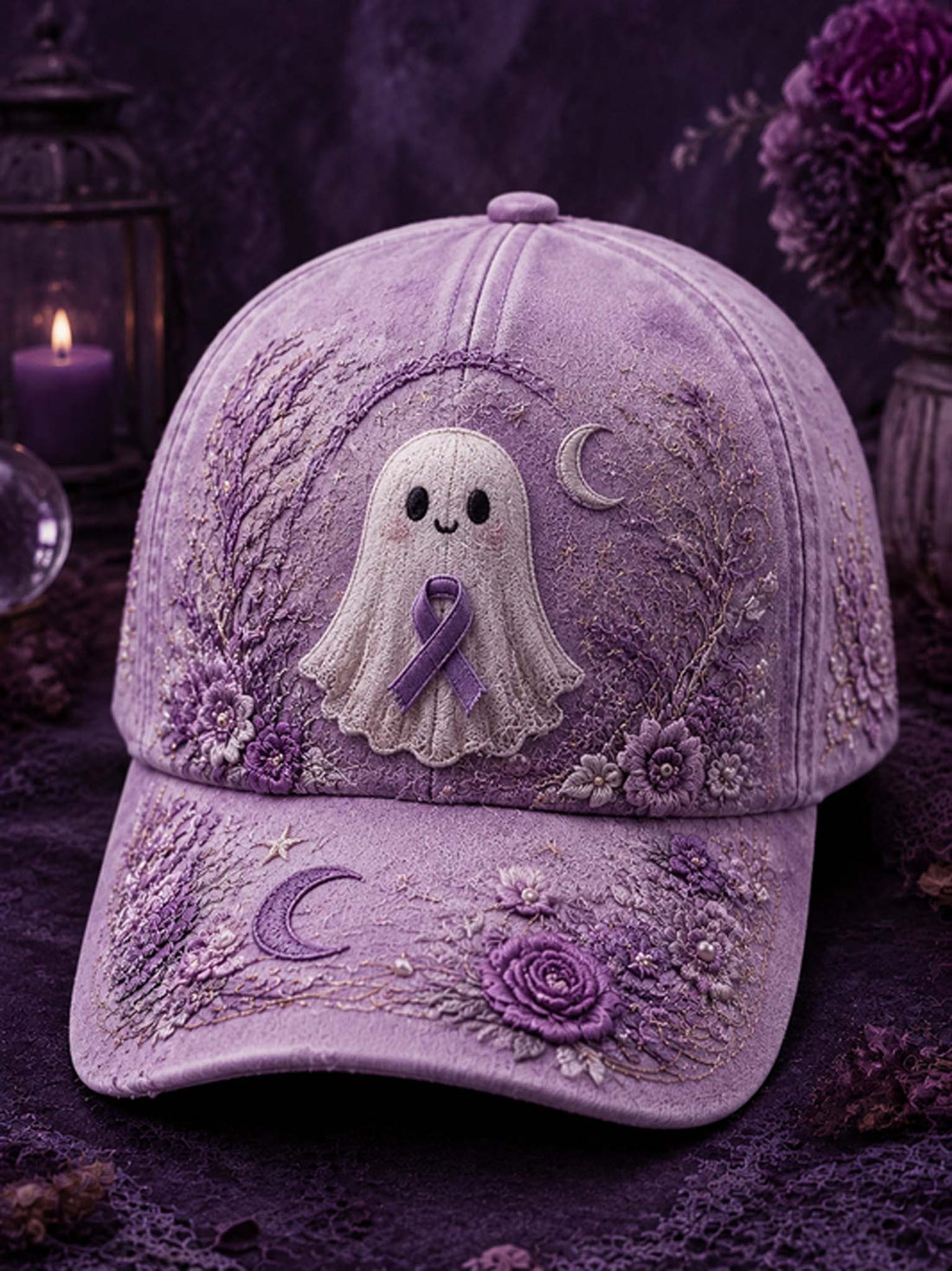 A lavender-purple embroidered baseball cap featuring a white ghost with a purple ribbon on the front, surrounded by floral and crescent moon embroidery, set against a dark purple background with candles and flowers.