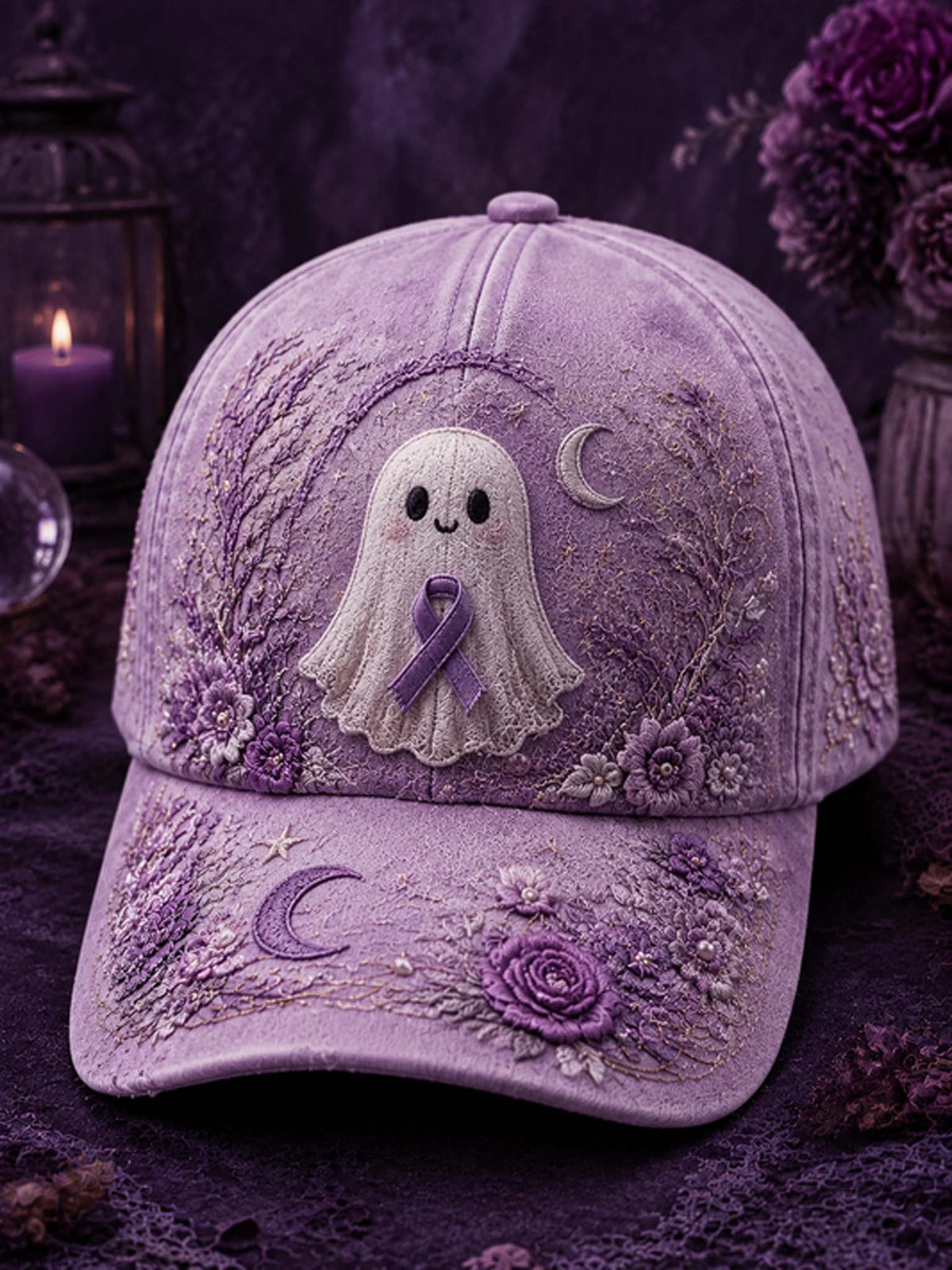 A lavender-purple embroidered baseball cap featuring a white ghost with a purple ribbon on the front, surrounded by floral and crescent moon embroidery, set against a dark purple background with candles and flowers.
