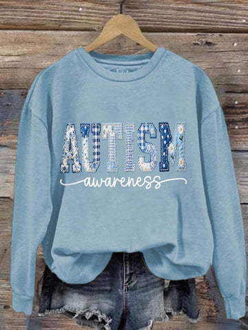 Light blue sweatshirt with 'Autism awareness' text on a wooden background