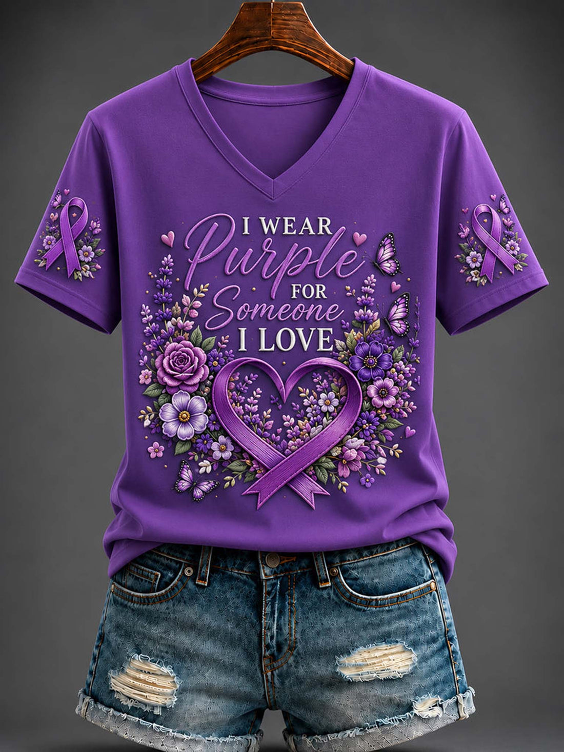 Women's purple V-neck shirt with purple awareness ribbons, floral heart frame, butterflies, and "I Wear Purple For Someone I Love" graphic paired with denim shorts.