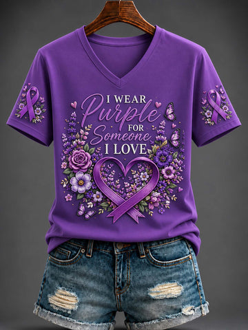 Women's purple V-neck shirt with purple awareness ribbons, floral heart frame, butterflies, and "I Wear Purple For Someone I Love" graphic paired with denim shorts.